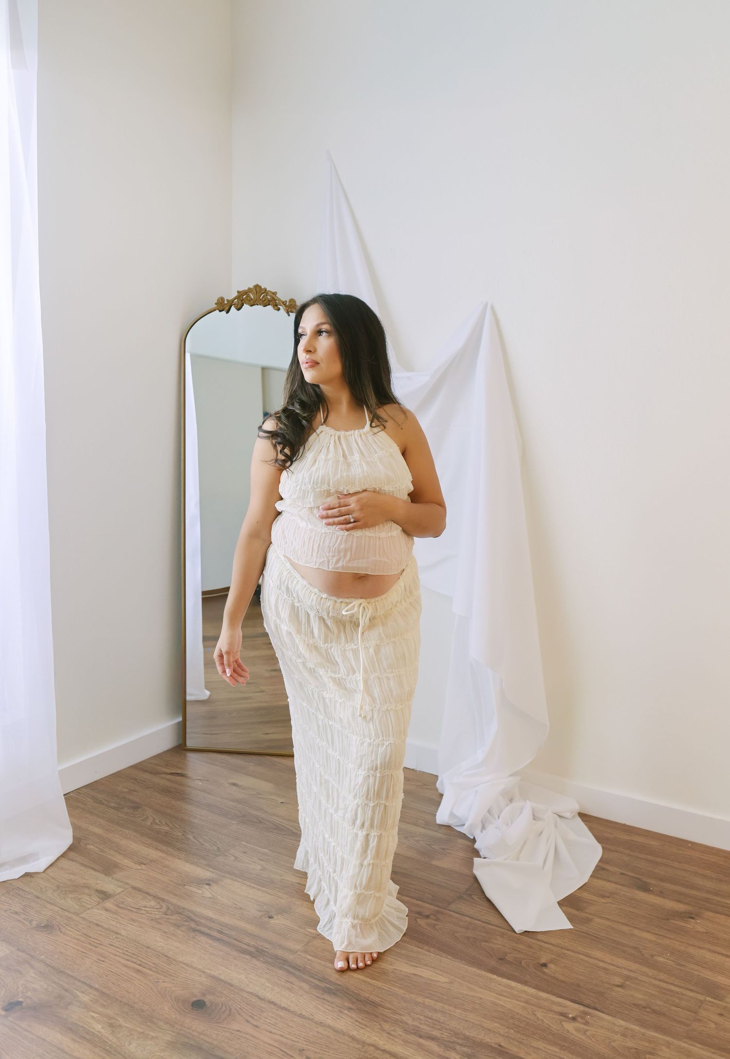 Artistic maternity portrait featuring a woman in flowing red fabric against a dark background.