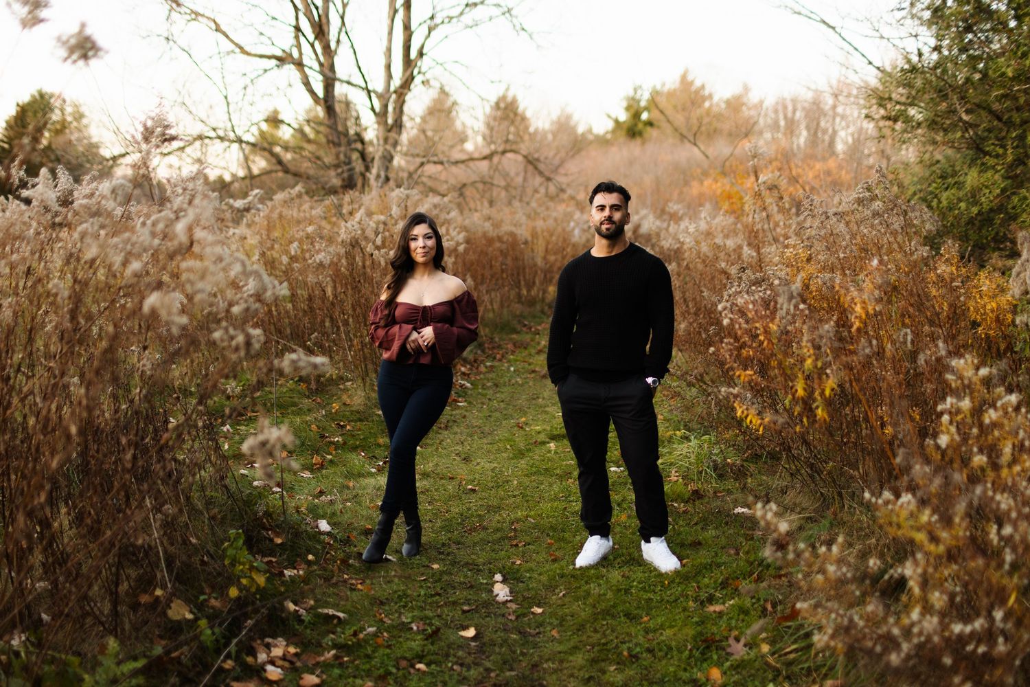 Couple sitting back to back on concrete ground in casual attire.