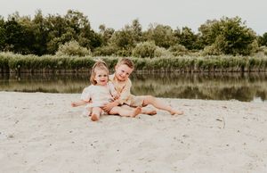Melissa Stuer Photography Moederschapsfotograaf Moerbeke Oost-Vlaanderen broer en zus jongen en meisje spelend in zand aan water portret
