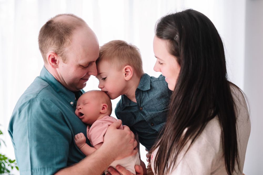 An intimate family moment as parents and child gather around their newborn baby.
