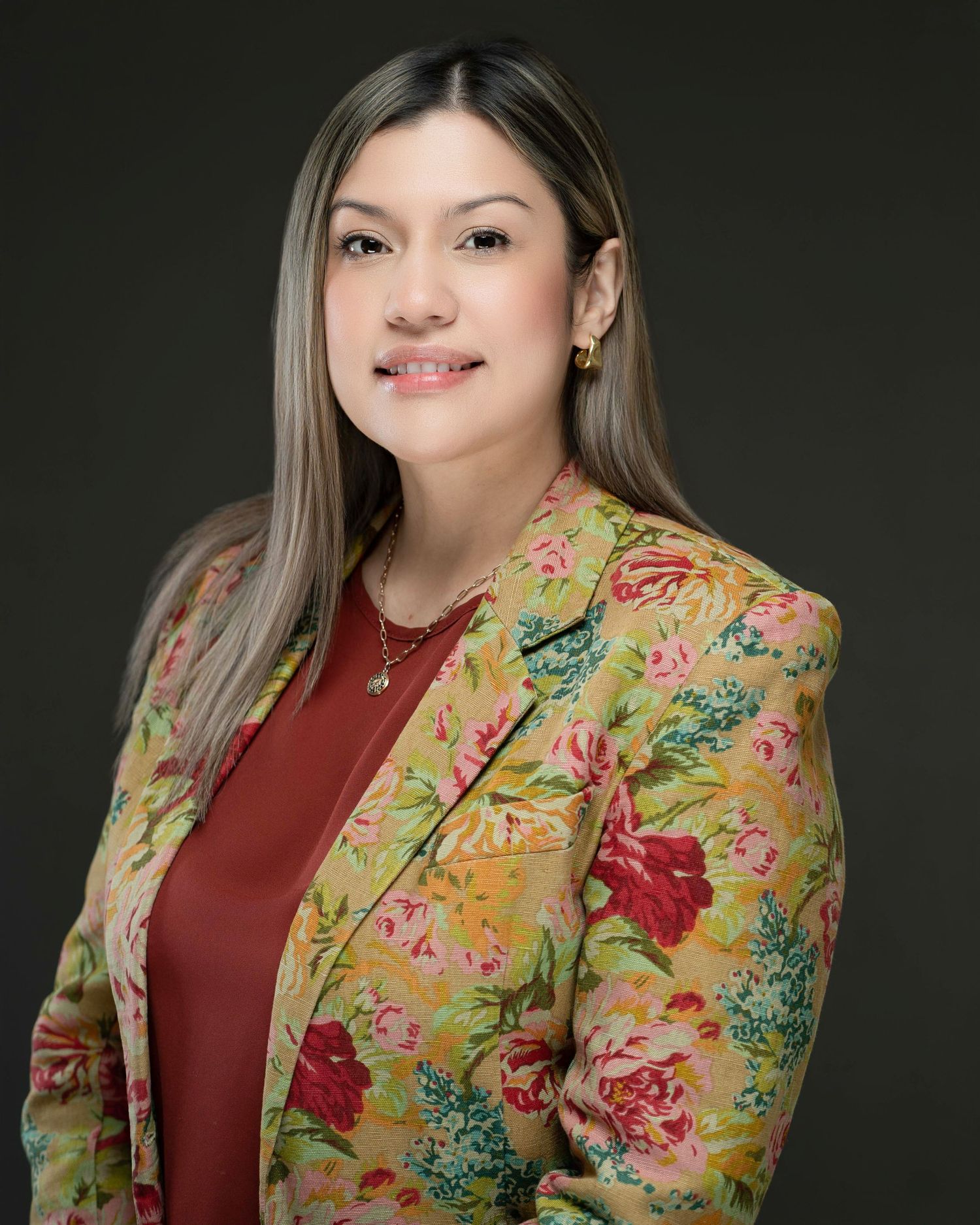 Professional portrait of someone wearing a red top and yellow floral print blazer against a dark background. Kelly Photography Atlanta