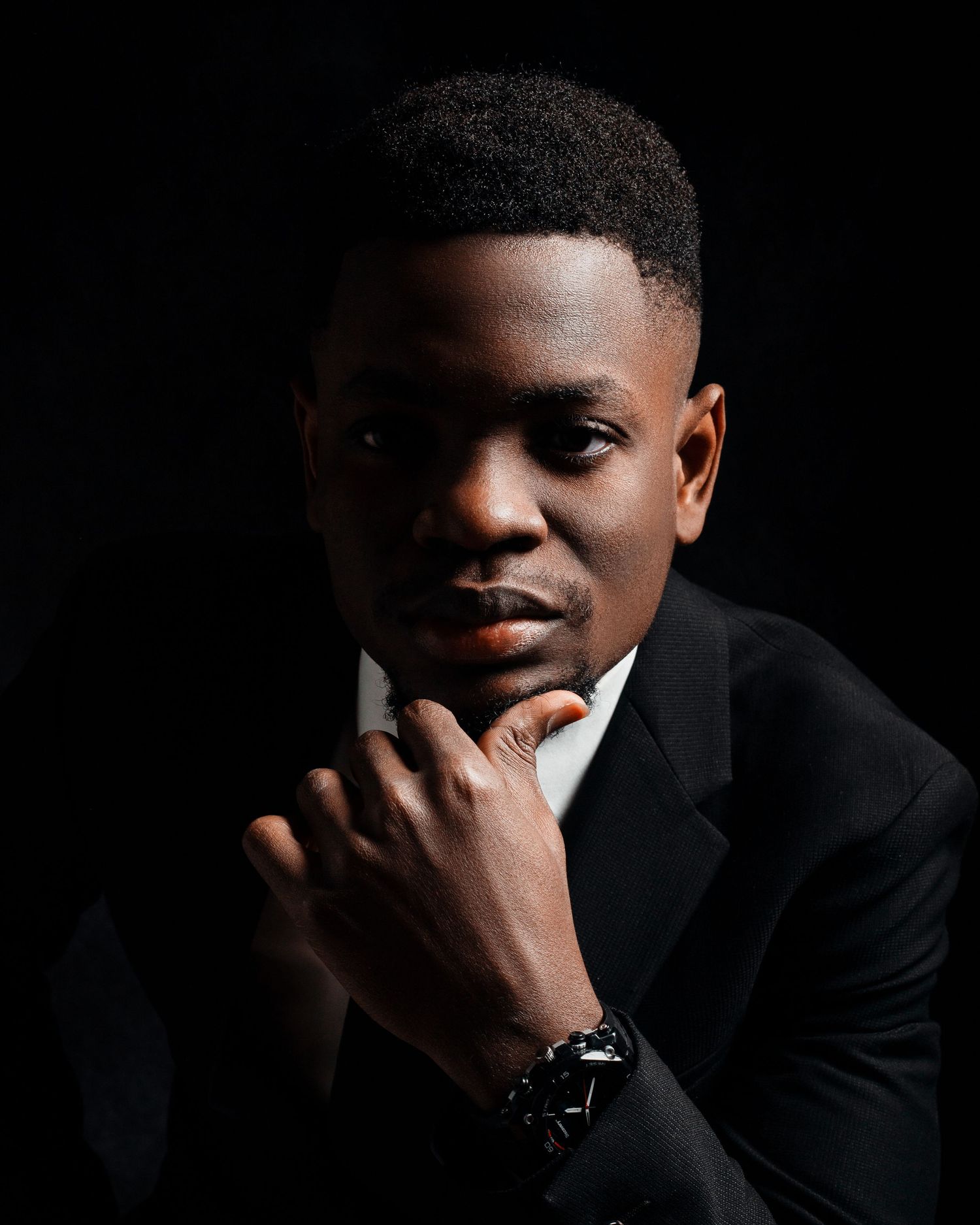 Professional studio portrait with dramatic lighting against dark background.