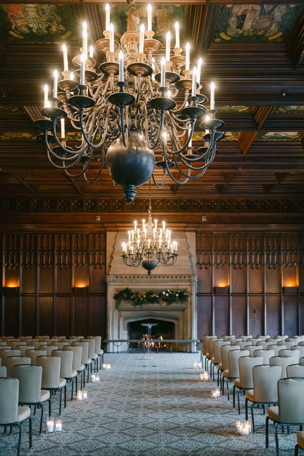Elegant indoor wedding ceremony setup with white chairs, chandeliers and wood-paneled walls in a grand hall. - University Club of Chicago