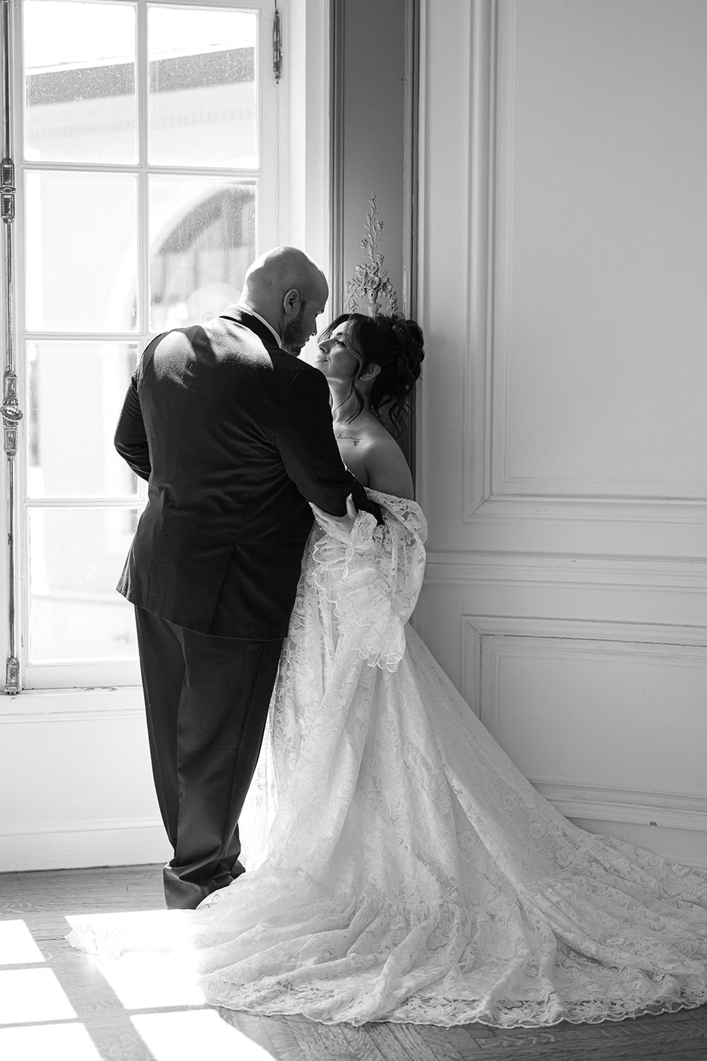 A sequence of black and white photos showing a couple in wedding attire leaning against a bright window. - The Armour House