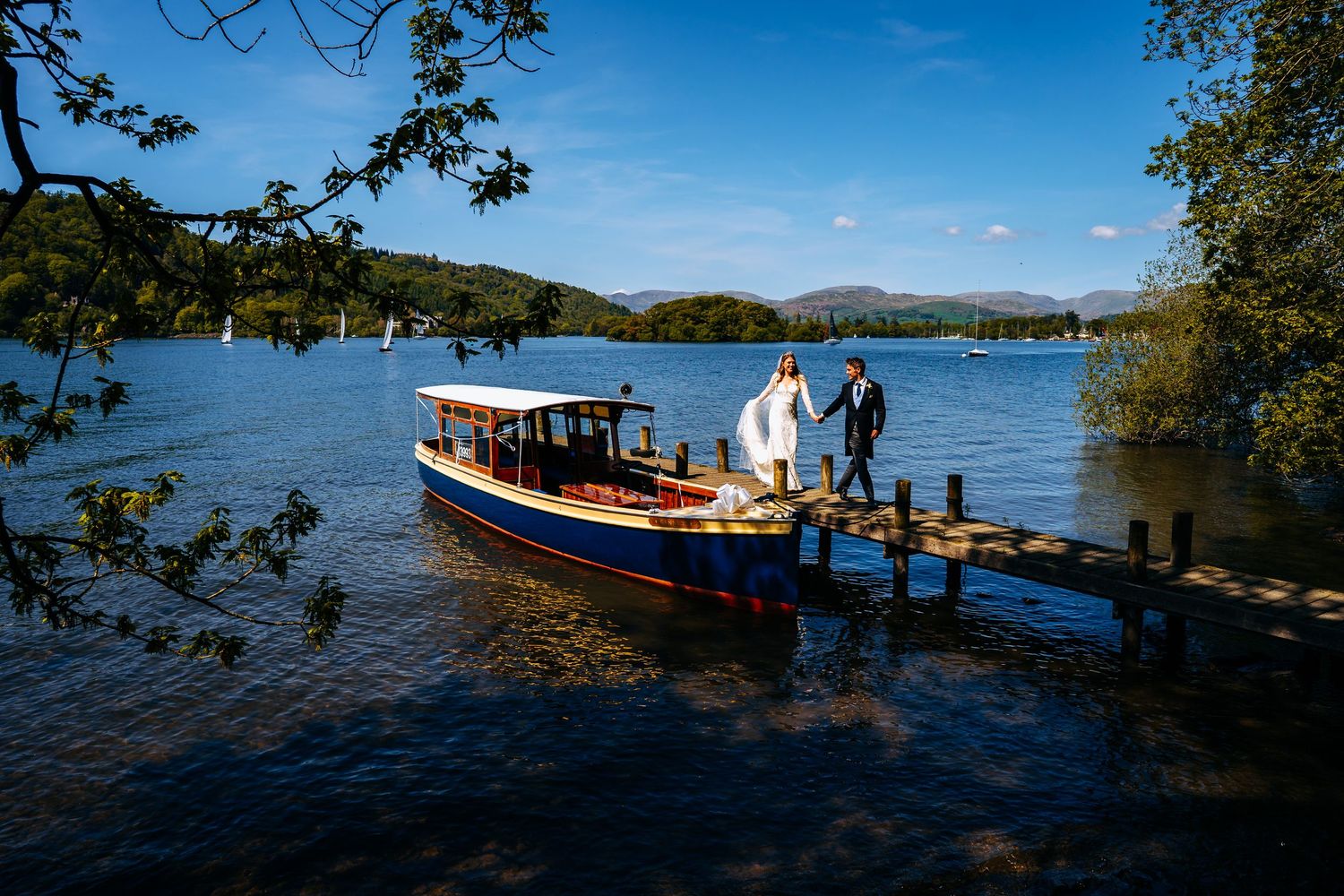 Lake District wedding photograph on a jetty on Windermere, th bride and groom disembarking from the boat to walk to their wedding reception.