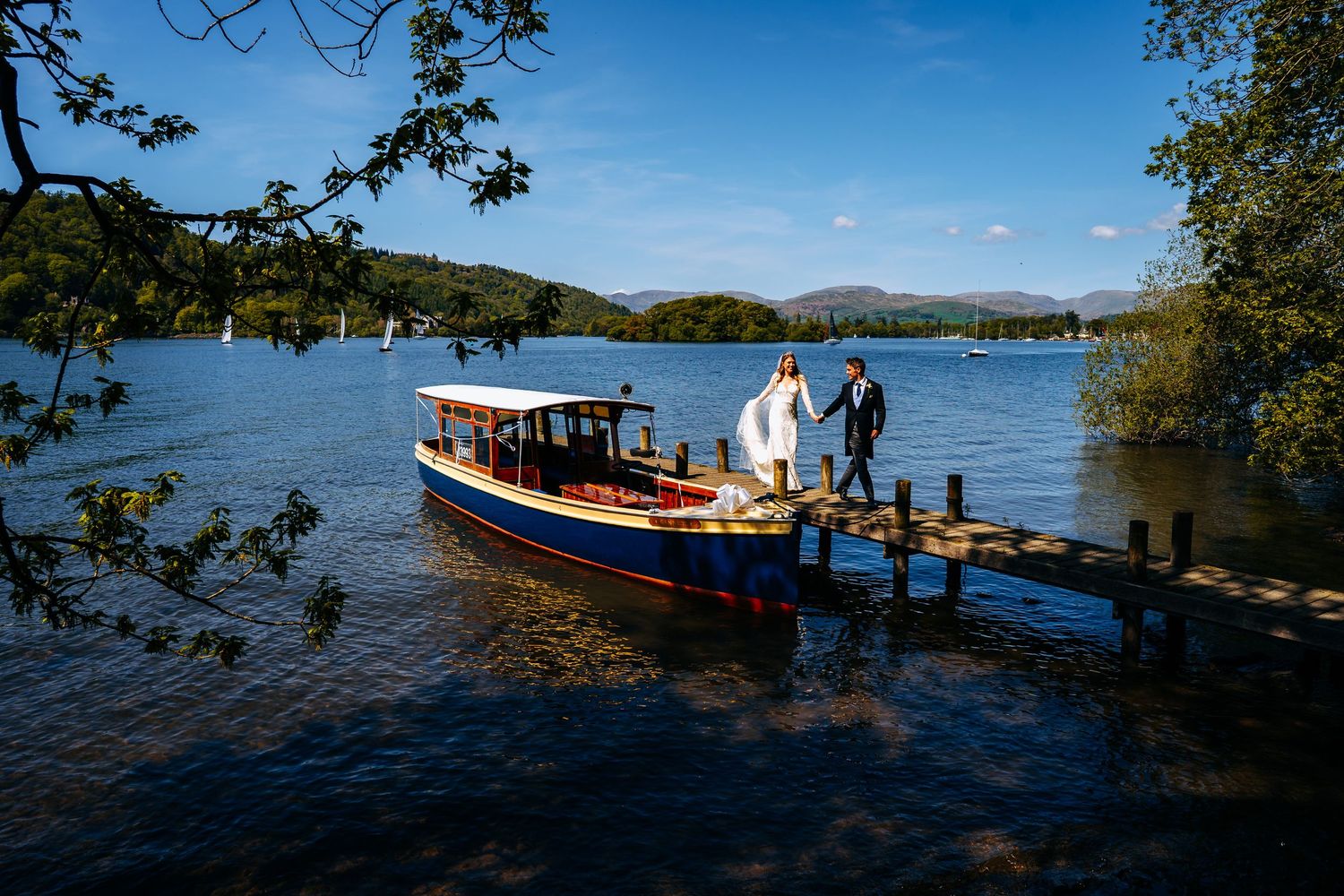 Lake District wedding photograph on a windermere Jetty, bride and groom disembarking boat to walk to their wedding reception.