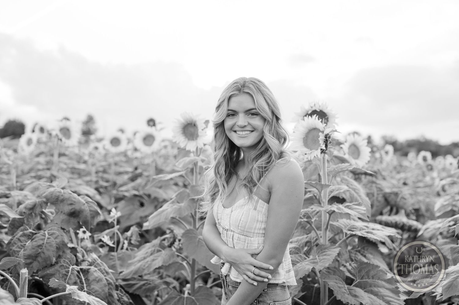 Black and white portrait in a blooming sunflower field with natural candid pose.