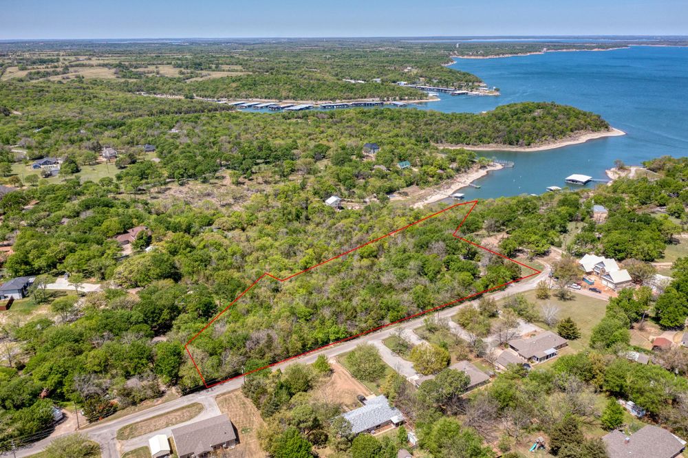 Scenic lakefront aerial view showing residential development nestled among trees near shoreline.