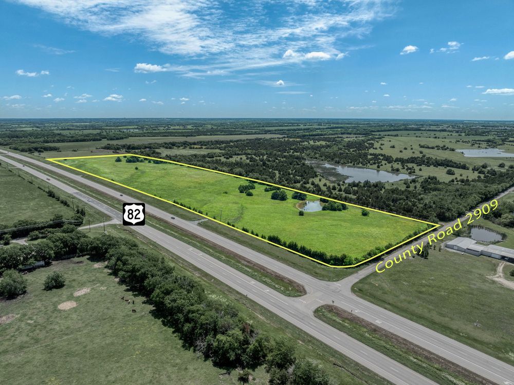Aerial view of a highway intersection surrounded by green fields and trees.