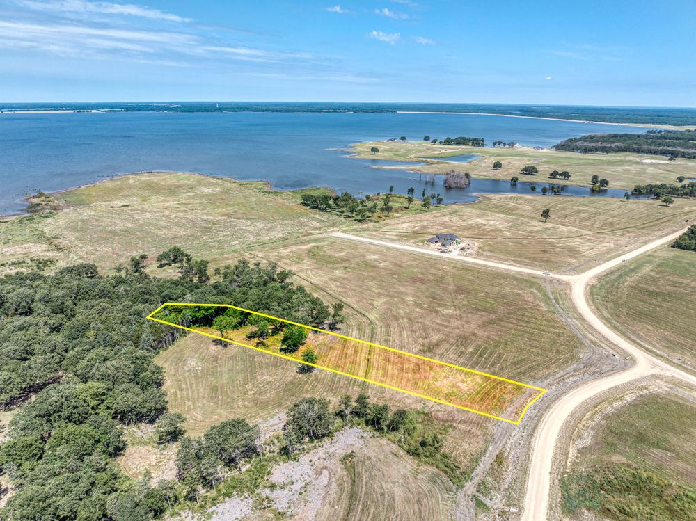 Aerial view of coastal property with marked parcels overlooking a large body of water.