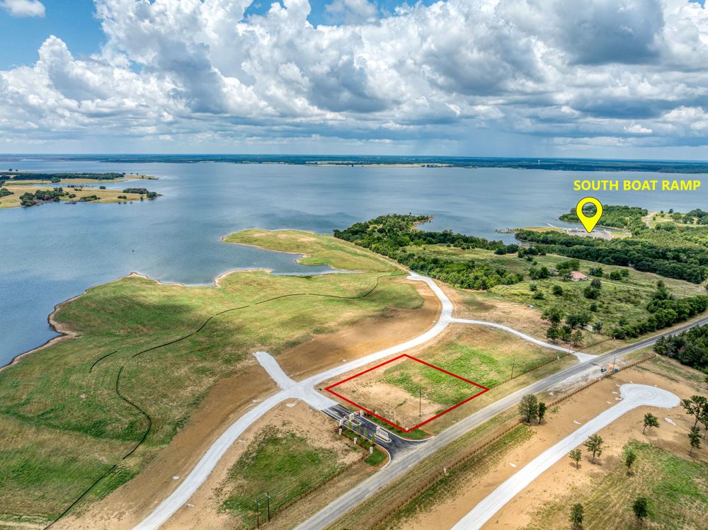 Drone shot of lakefront development with roads and peninsulas under cloudy sky.