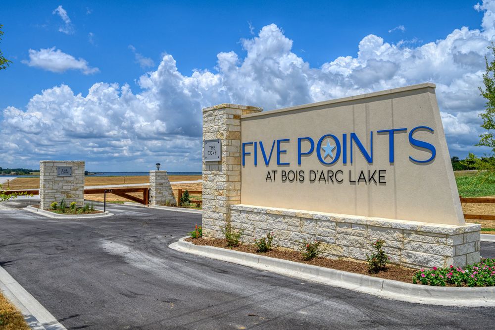 Entrance sign and stone monument for Five Points development under blue sky with white puffy clouds.