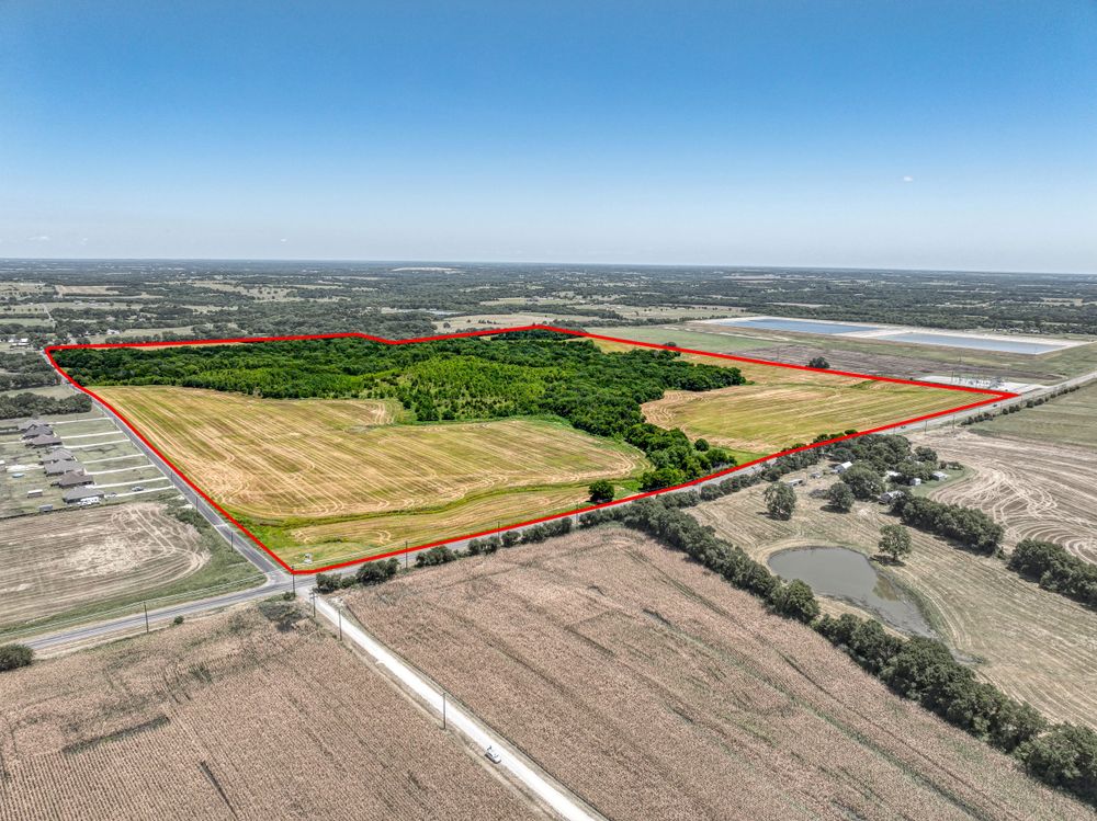 Aerial view of agricultural land parcels divided by roads with highlighted property boundaries.