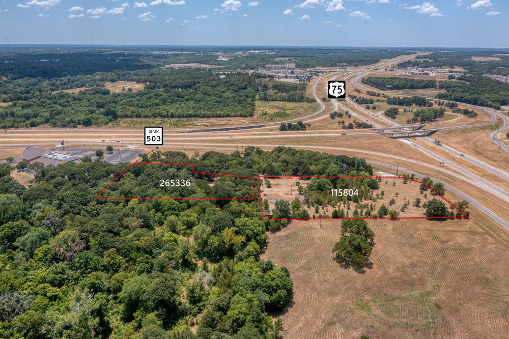 Aerial photograph of highway intersection surrounded by wooded areas and open land.