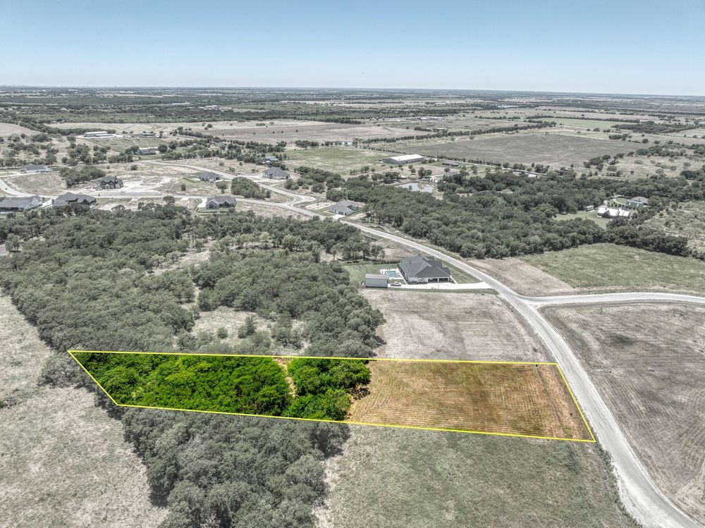 Bird's eye view of rural property with highlighted lots surrounded by trees and winding roads.
