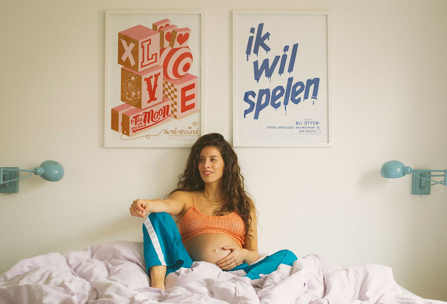 Interior room with posters on wall and white bedding in natural lighting.
