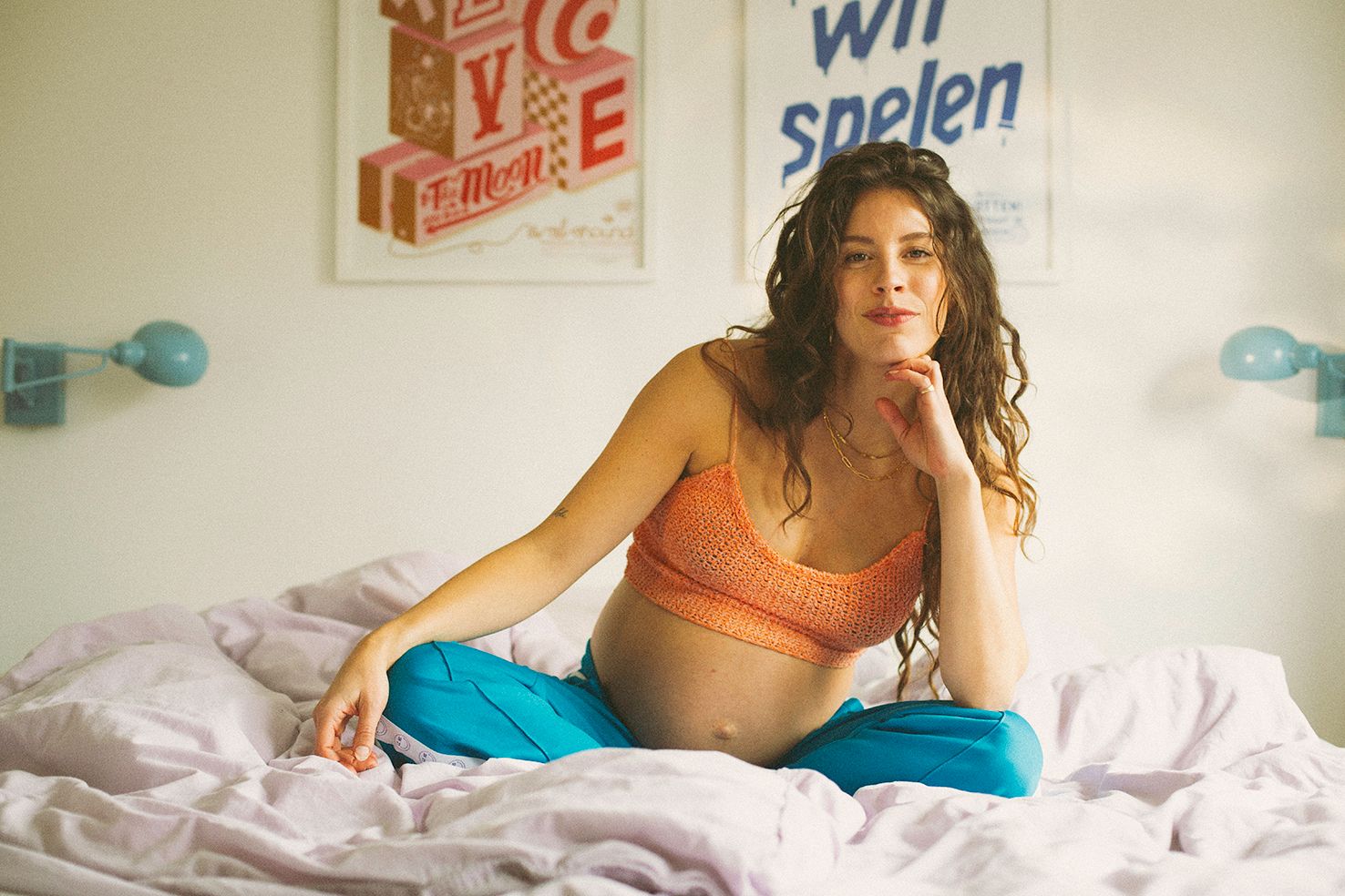 Person relaxing in bed with soft lighting and vintage decor in background.