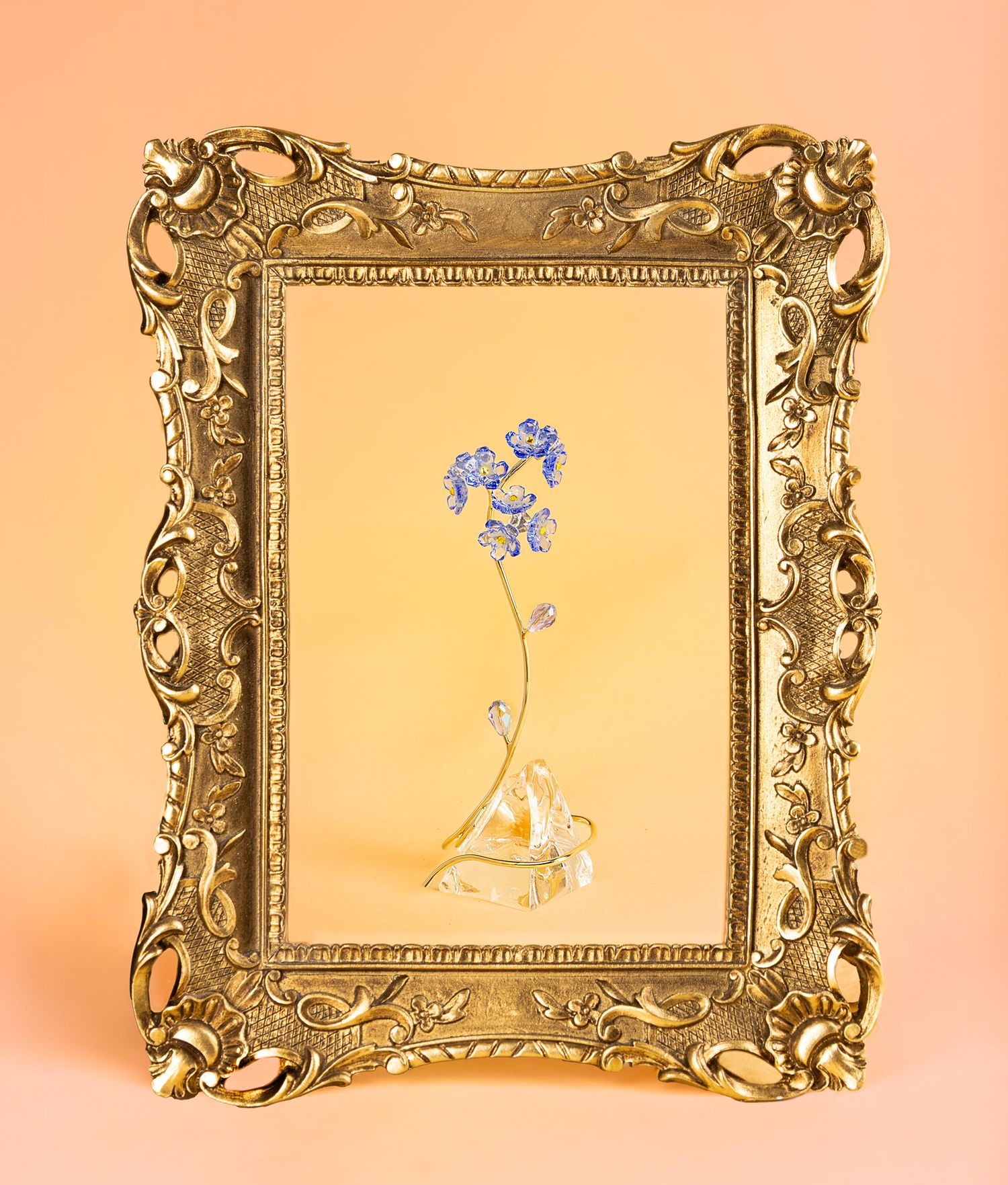 Crystal flower in front of a yellow and pink backdrop, with a gold frame in photo for a frame within a frame effect