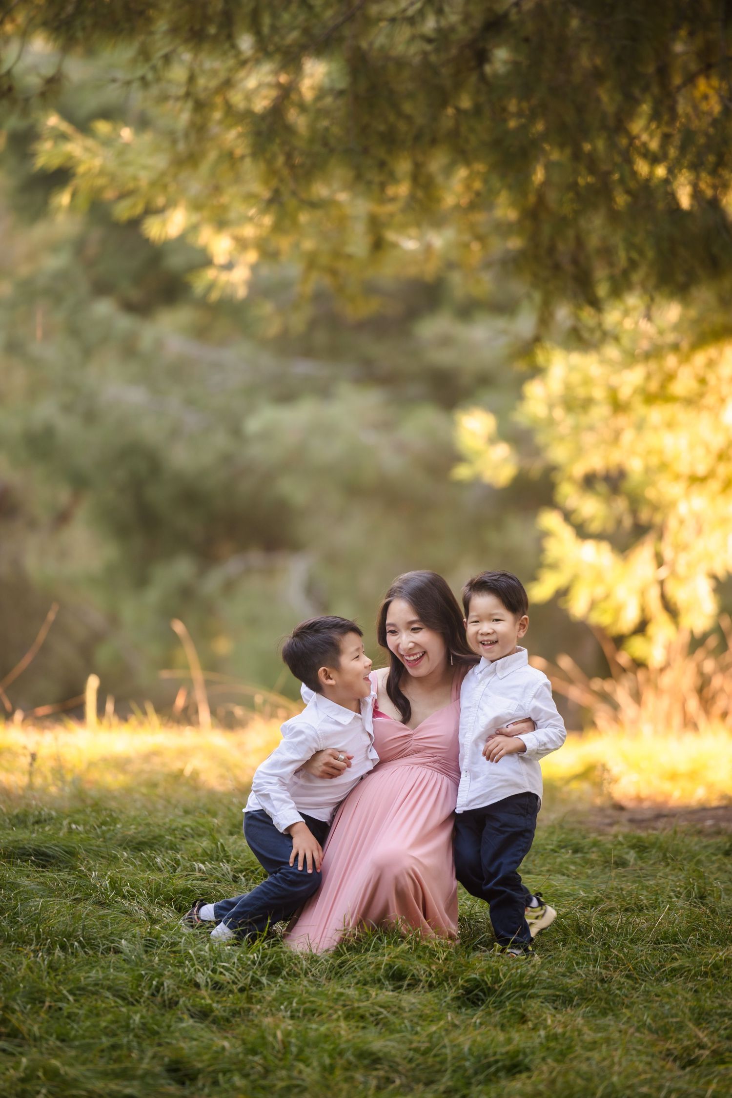 A heartwarming family moment captured in golden sunlight under trees.