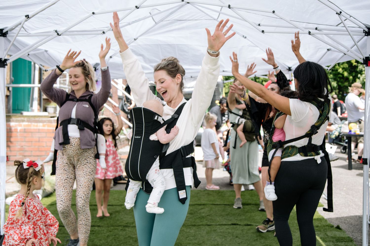Dancers raise their arms in synchronous movement during an outdoor performance.