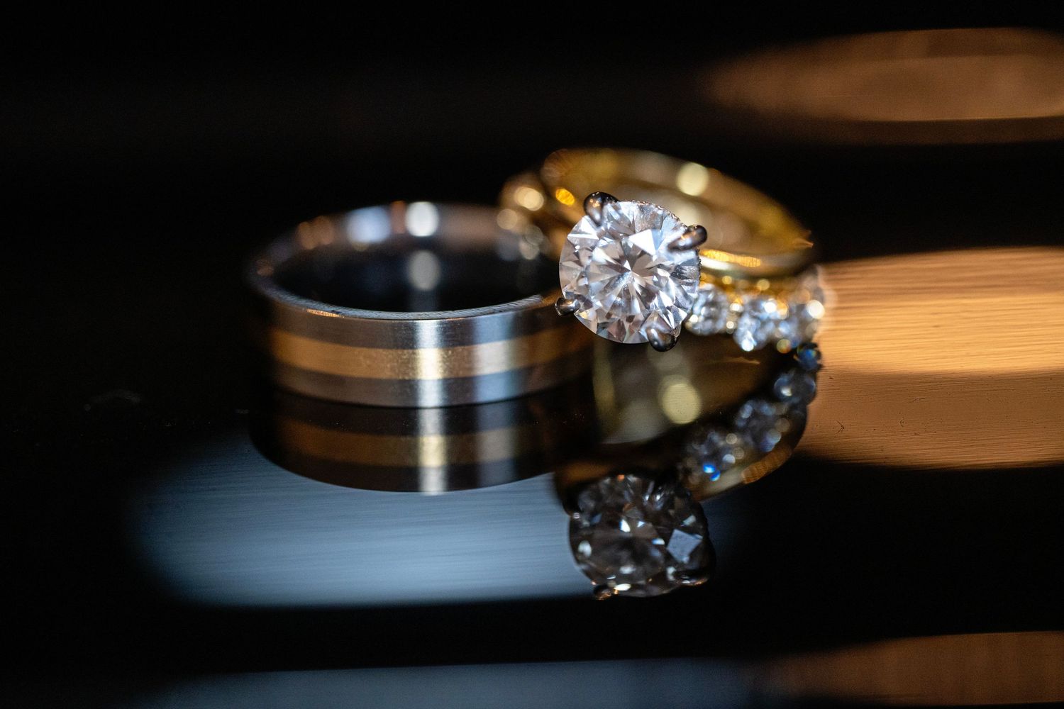 Close-up of wedding rings with decorative paper flower in soft focus background.