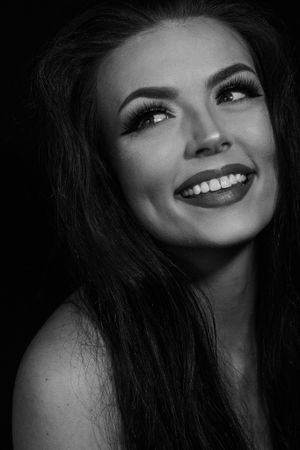 Black and white close-up portrait of a smiling woman with long dark hair and dramatic eye makeup.