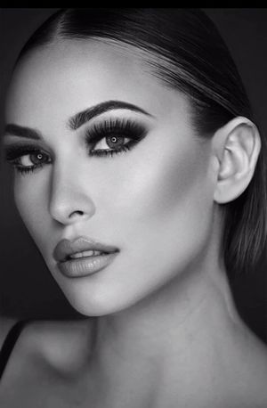 Black and white close-up portrait of a woman with dramatic smoky eye makeup and sleek hair.