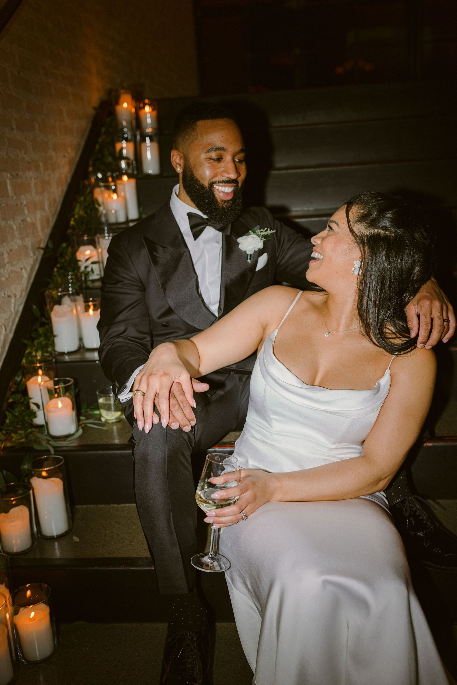 A romantic candlelit wedding moment on stairs decorated with glowing candles in glass holders.