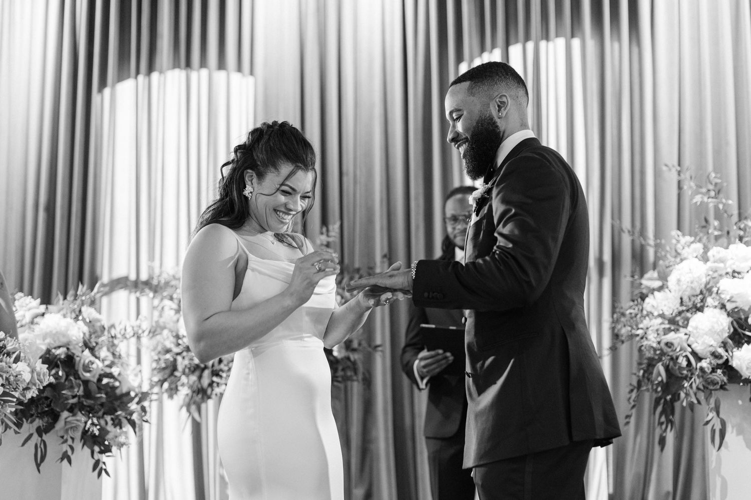 Black and white photo of wedding ceremony with couple exchanging vows.