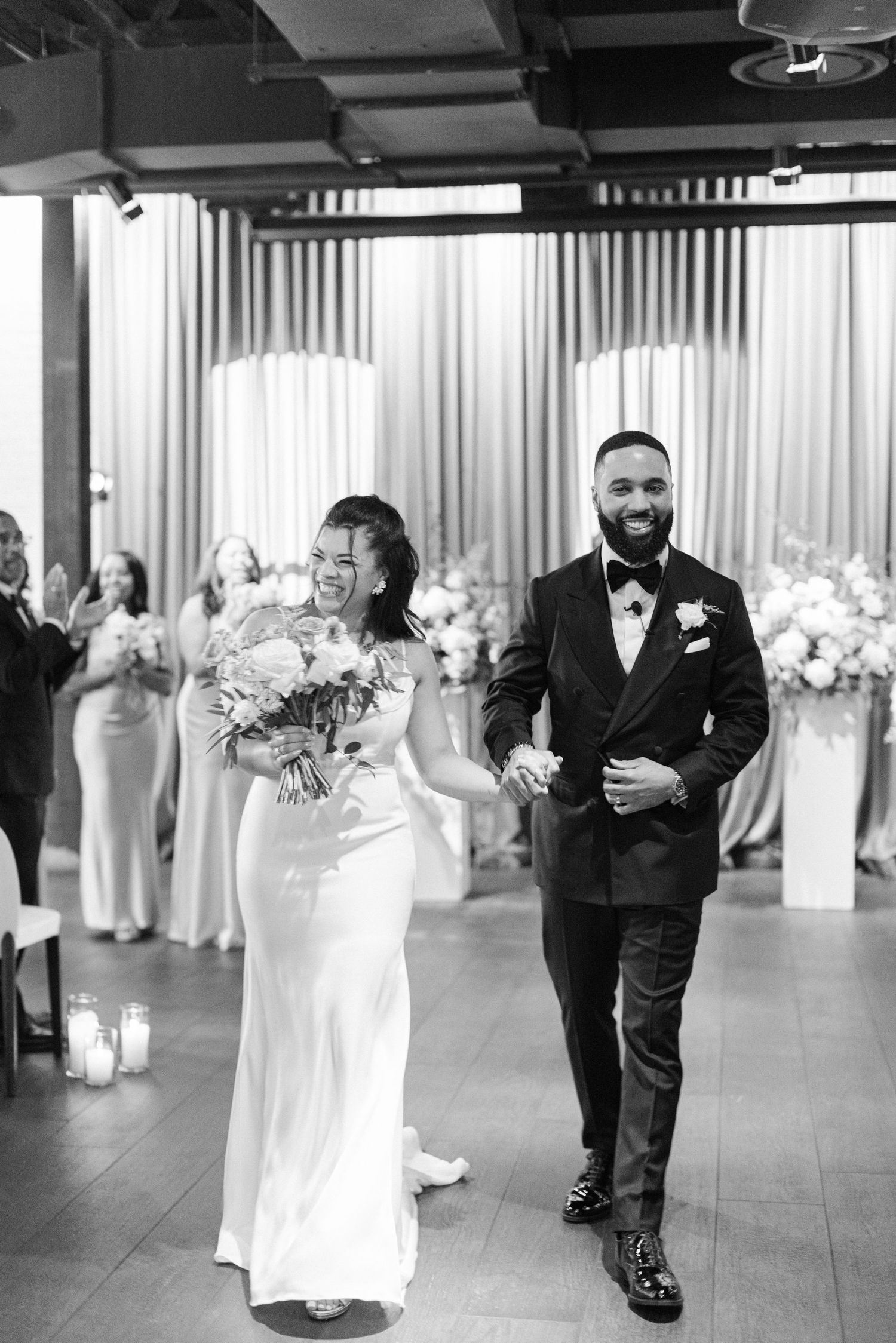 Happy couple walks down aisle after wedding ceremony in black and white.