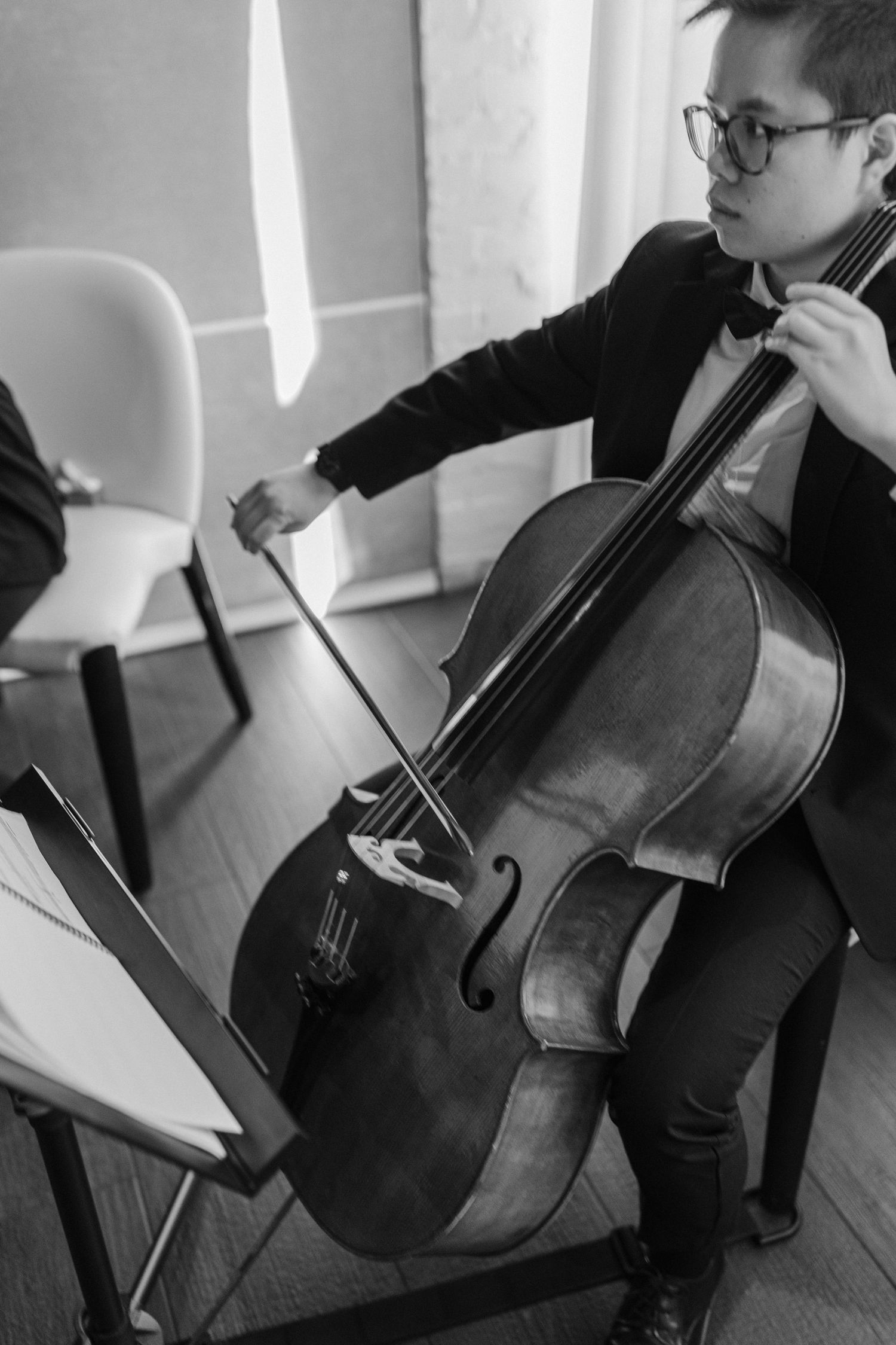 Black and white photo of musician playing cello during performance.
