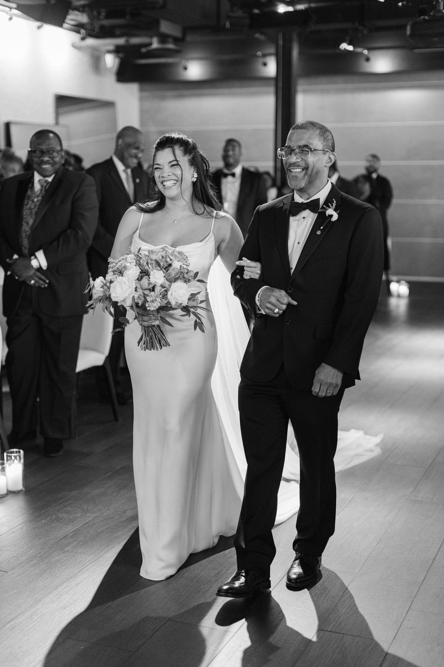 Black and white wedding ceremony photo showing processional down aisle.