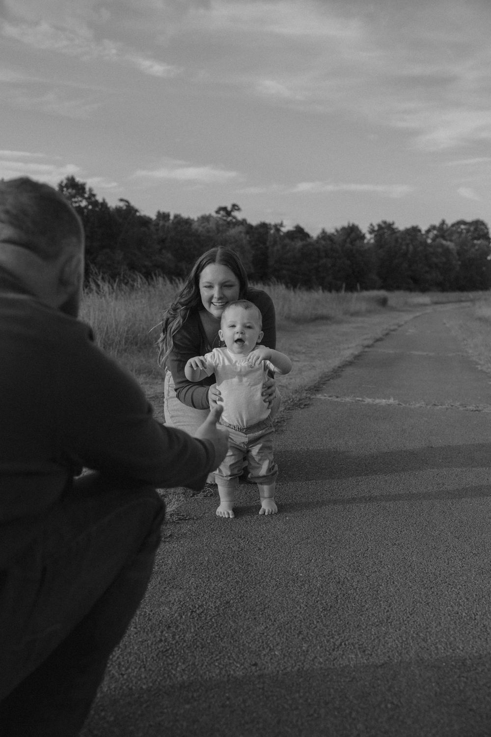 Black and white photo of outdoor family moment on a paved path.