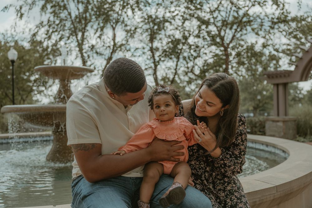 Family sharing a tender moment together by a fountain in a park.