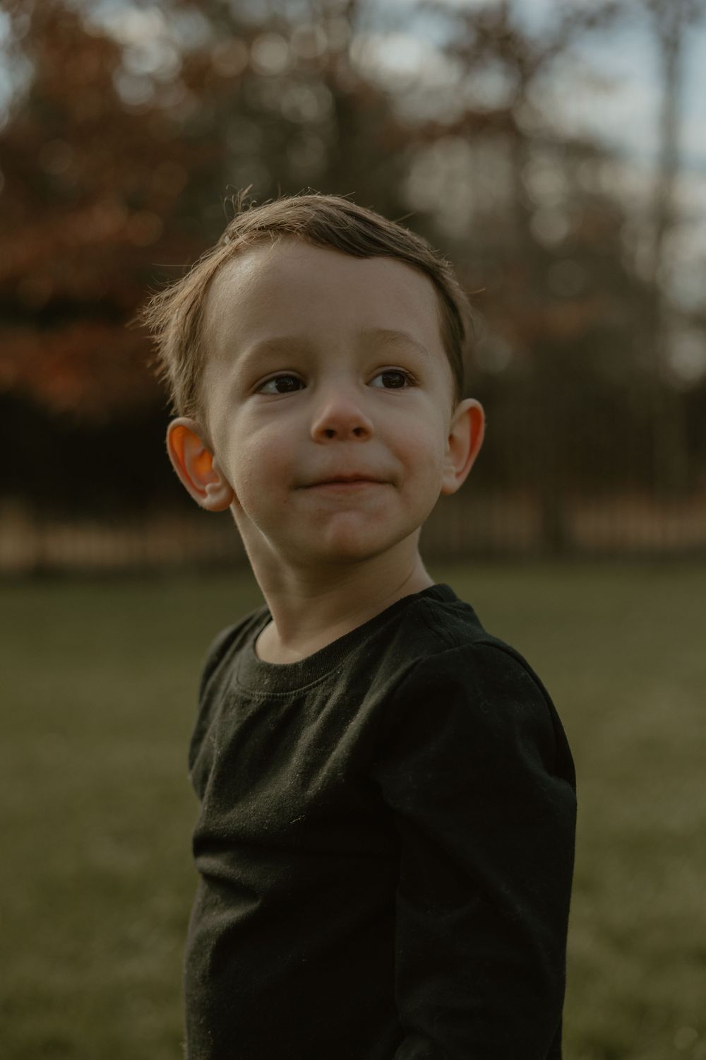 Close-up portrait of child in black shirt with natural autumn backdrop.
