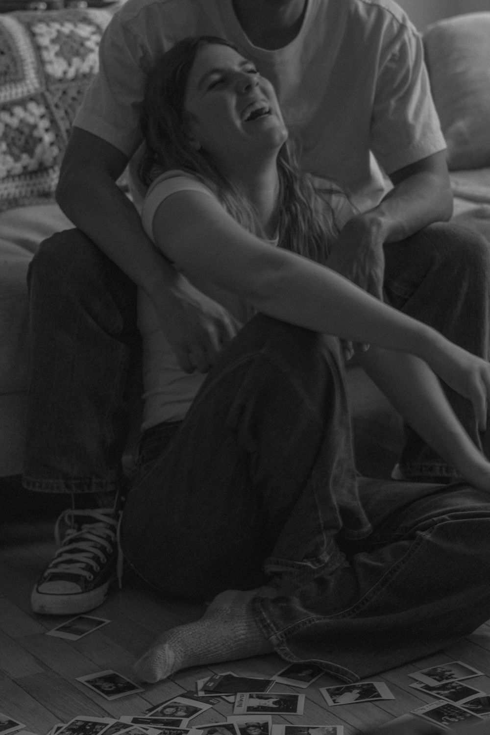 A black and white photo captures a joyful moment between two people surrounded by photographs.