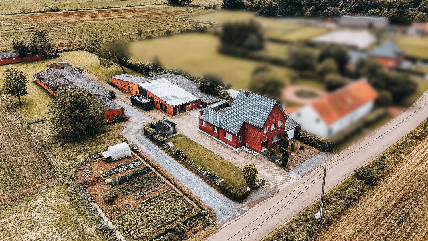 Luchtfoto vanuit de lucht van een landelijke boerderij met rode gebouwen en omliggende velden.