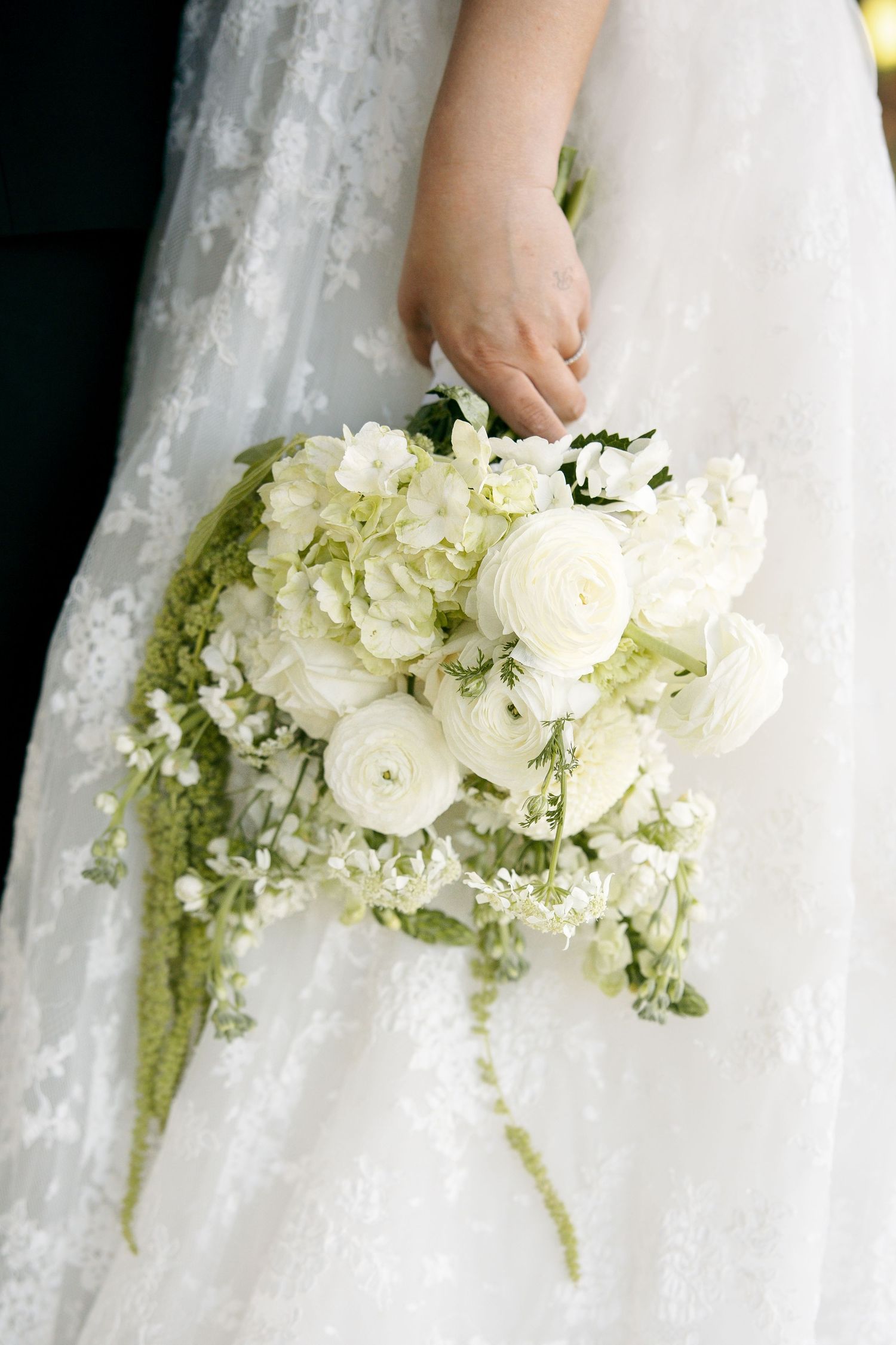 Close-up details of white lace wedding dress and diamond engagement ring.