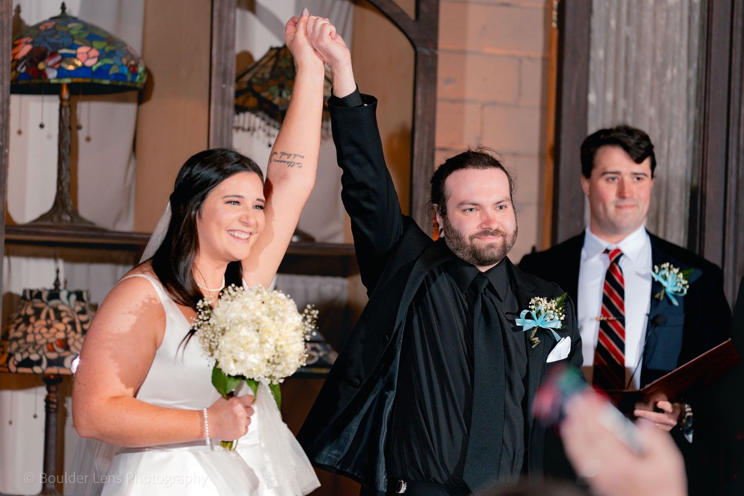 Joyful wedding celebration moment with enthusiastic newlyweds raising hands in victory.