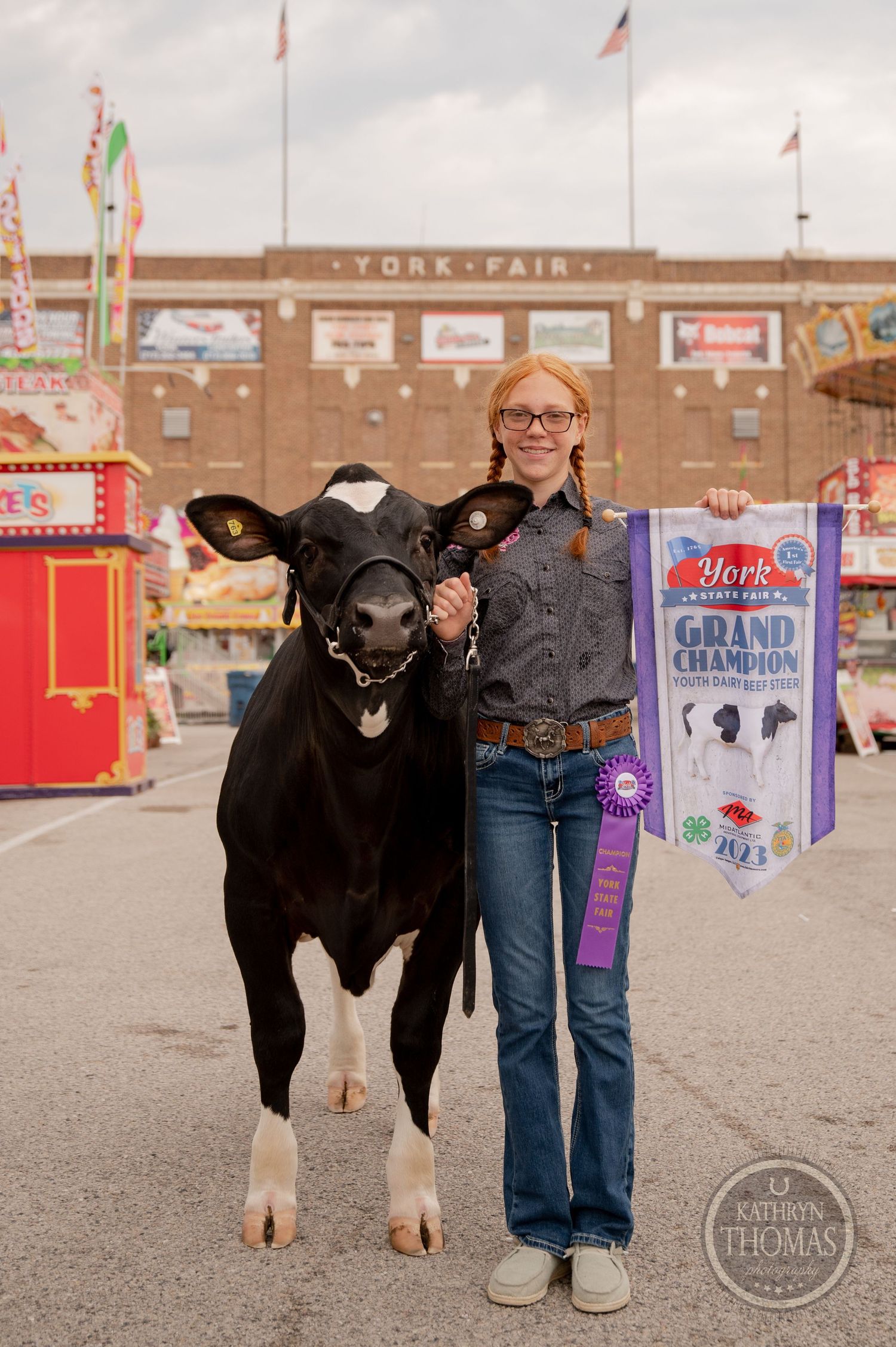 A prize-winning black and white cow stands with handler at the York Fair entrance.