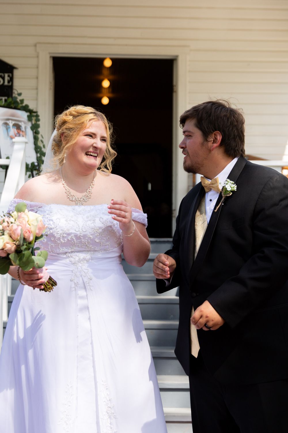 Joyful wedding moment captured on white porch steps of historic building.