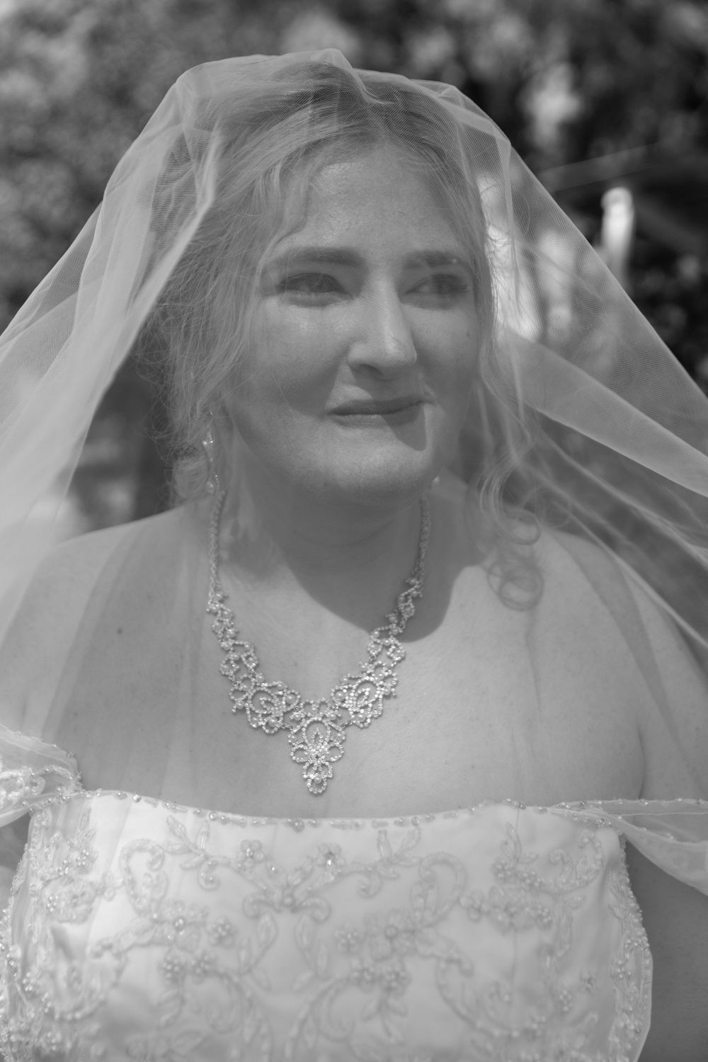 Black and white portrait of bride wearing delicate veil and crystal necklace.