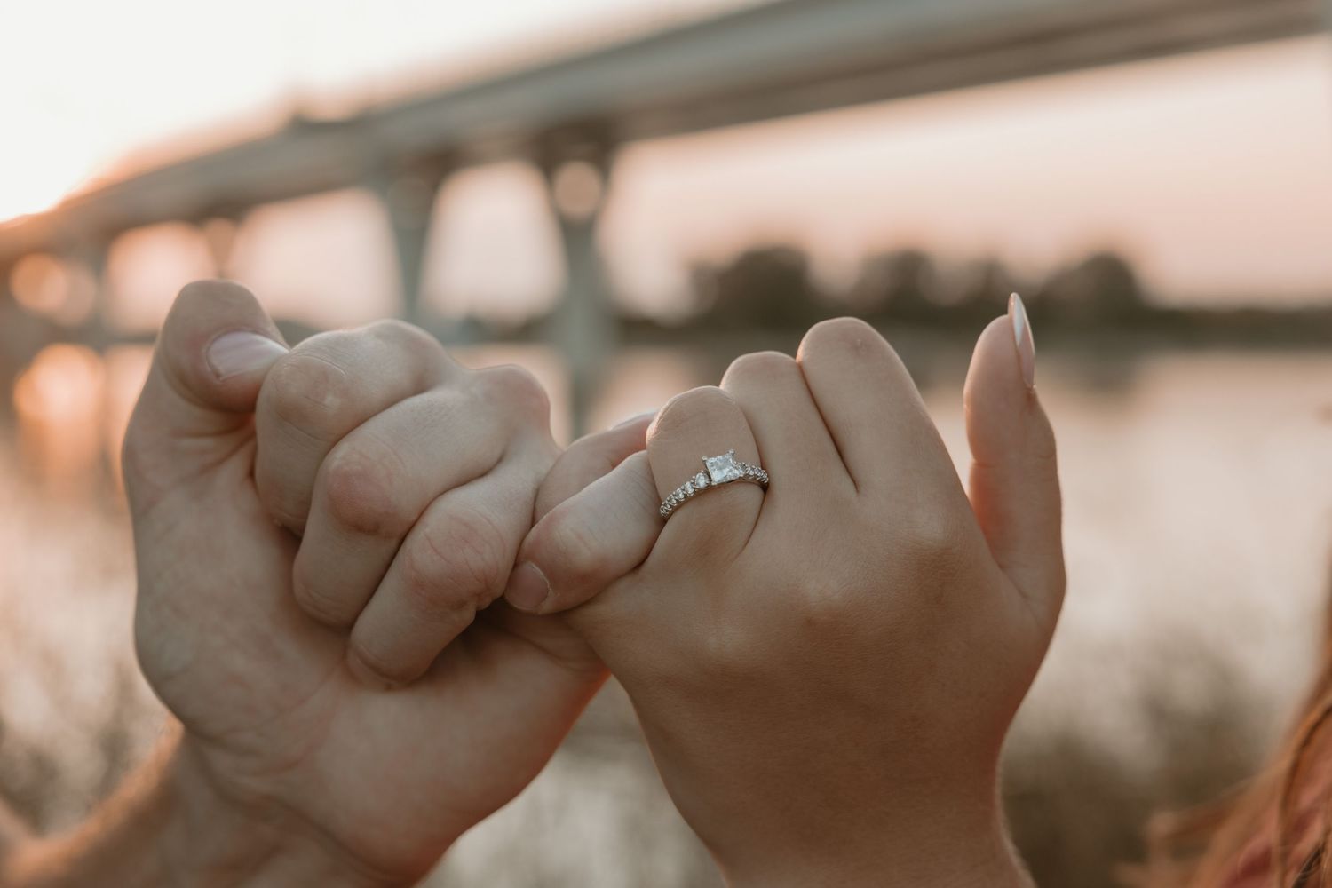Engaged couple pinky promise showing wedding ring by the Missouri River at sunset in Bismarck North Dakota engagement photography