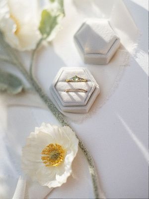 Wedding band and engagement ring in a box surrounded by white poppy flowers