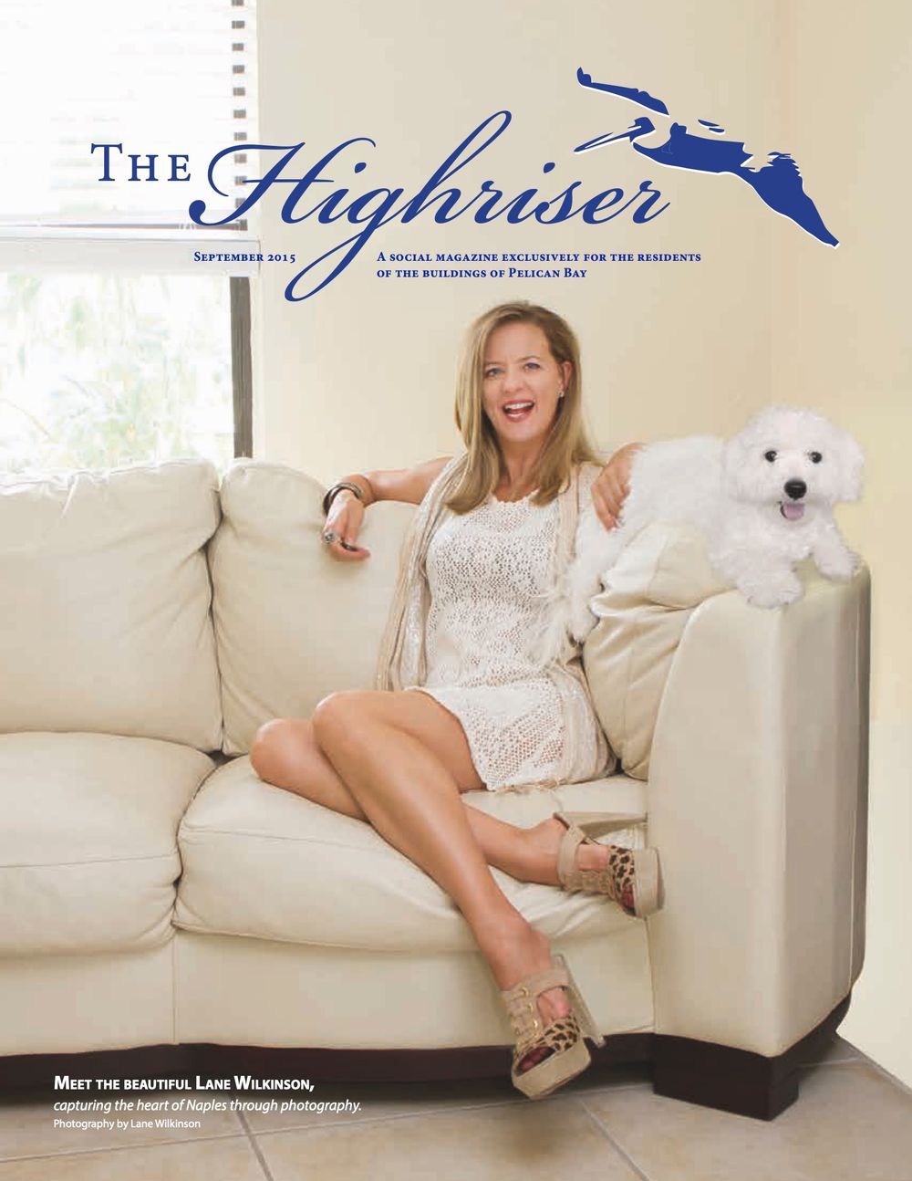 Blonde woman in white lace dress poses on cream sofa with white poodle for The Highriser magazine cover.