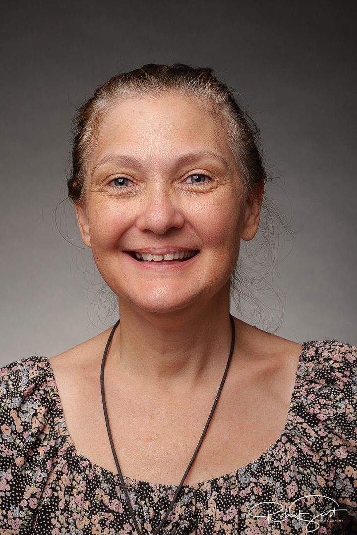Studio headshot portrait against grey background.