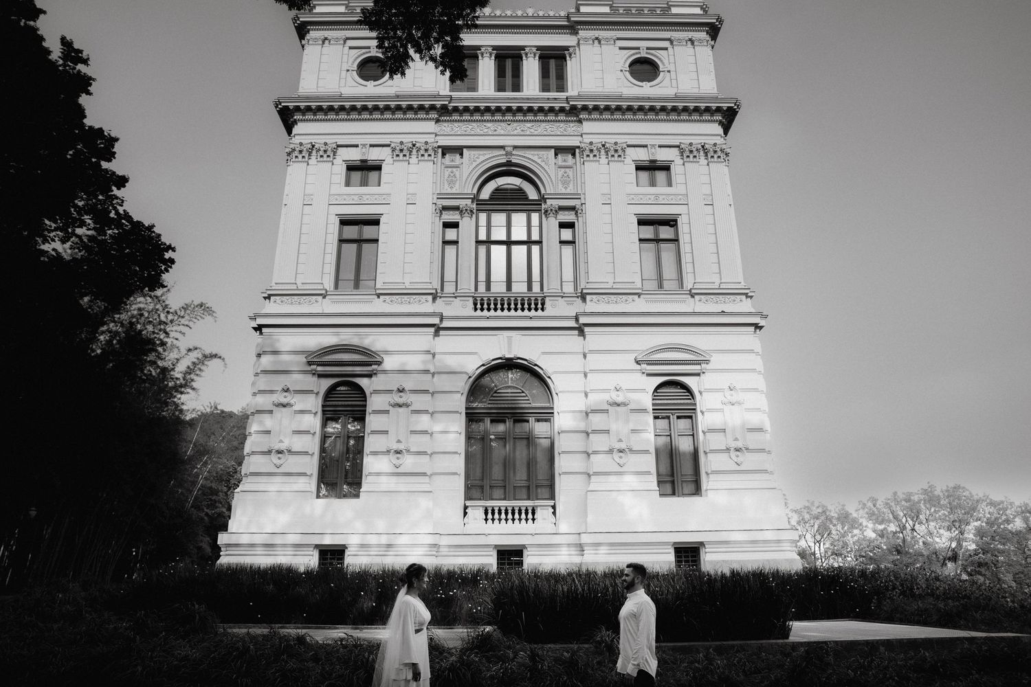 Classical white building with arched windows and ornate architectural details in black and white.