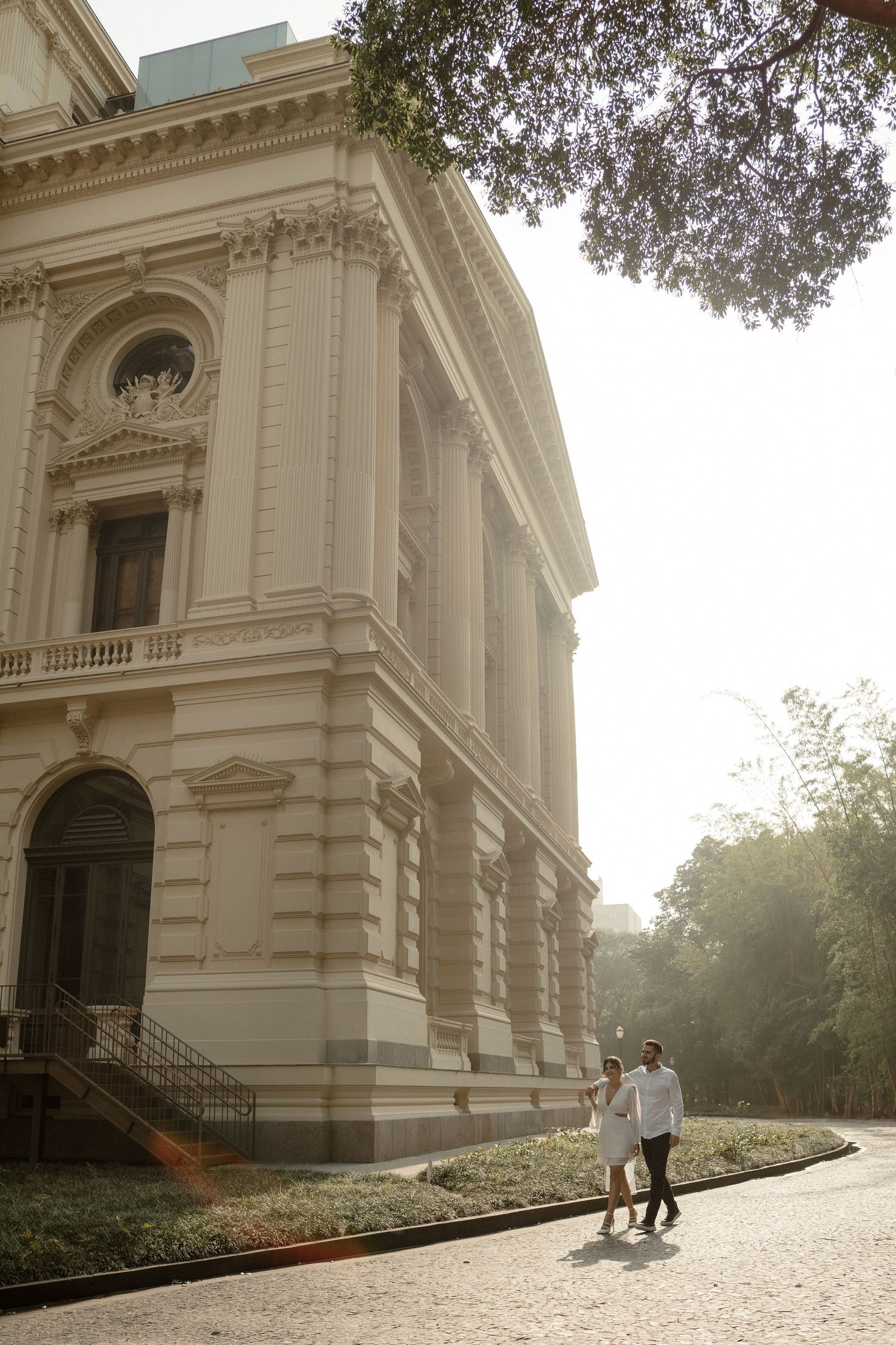 Couple standing together outside a classical architecture building with ornate details and columns.