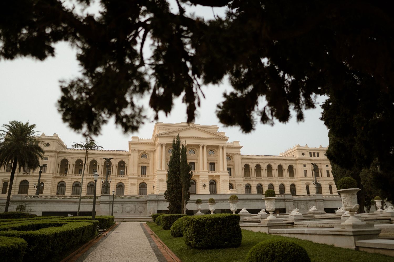Panoramic view of a historic government building with palm trees and manicured grounds.