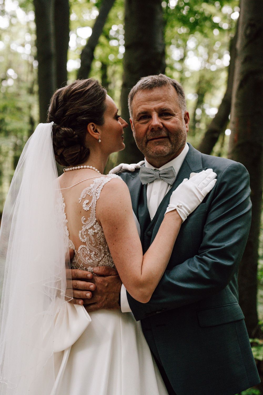 Romantic wedding moment captured in a forest setting.